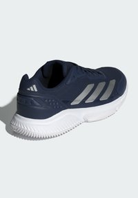 Męskie buty sportowe w kolorze granatowym z srebrnymi paskami. Posiadają teksturowaną cholewkę, wyściełany kołnierz oraz białą gumową podeszwę z wzorem w zygzak.