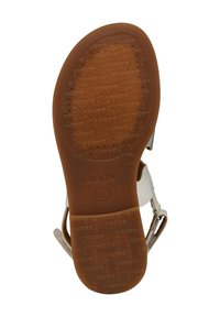 Suela de goma marrón con un patrón texturizado, con la marca "GEOX" en relieve. Delgadas correas blancas y plateadas unidas a la parte superior.