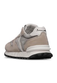 Sneaker in suede beige con dettagli in tessuto grigio, chiusura con lacci e tallone bianco. Presenta una suola in gomma nera testurizzata.