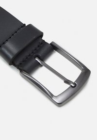 Curea din piele neagră cu o cataramă metalică strălucitoare, rectangulară. Prezintă o textură netedă și o cusătură ordonată pe margini.