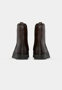 Bocanci din piele maro, până la gleznă, cu o textură netedă, vârf pătrat și talpă din cauciuc negru. Include mânere pentru tragere și mici accente perforate.