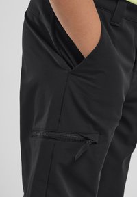 Pantalons noirs à texture lisse avec une poche latérale à fermeture éclair et une ouverture latérale inclinée pour plus de commodité.