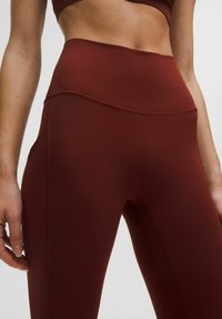 Vysoké legíny priliehajúceho strihu v hĺbokej burgundskej farbe. Vyrobené z hladkej, elastickej látky s plochými švami pre väčšiu odolnosť.