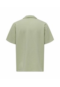 Gaiši zaļa īsroku krekls ar tekstūru un apkakli, redzams no aizmugures uz balta fona.