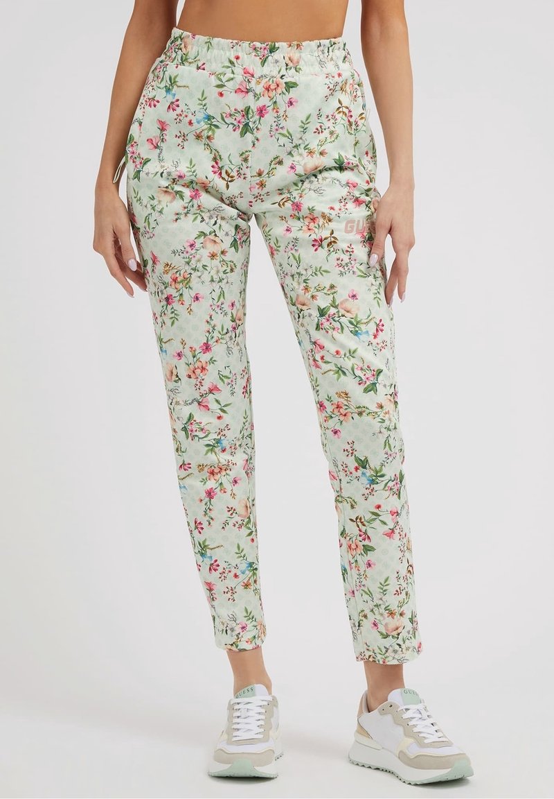 Pantalons floraux vert clair avec une taille élastique. Présente des fleurs multicolores, une coupe slim et un léger éclat. Associé à des baskets blanches.