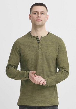 Zelená long-sleeve henley košeľa s textúrovanou látkou, ktorá má placket s čiernymi gombíkmi a manžety, a okrúhly výstrih.