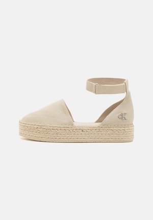 Beige espadrille-sandal med lukket tå, ankelrem, flettet jutesål med platform og "cK"-logo på hælen.