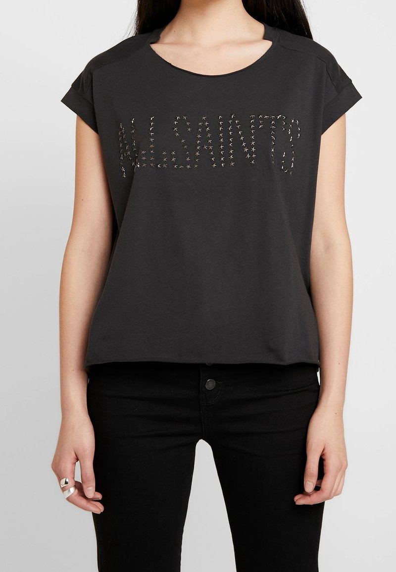 Svart bomullsplagg med korta ärmar och bred rund halsringning, prytt med ordet "ALLSAINTS" dekorerat med metalliska nitar.