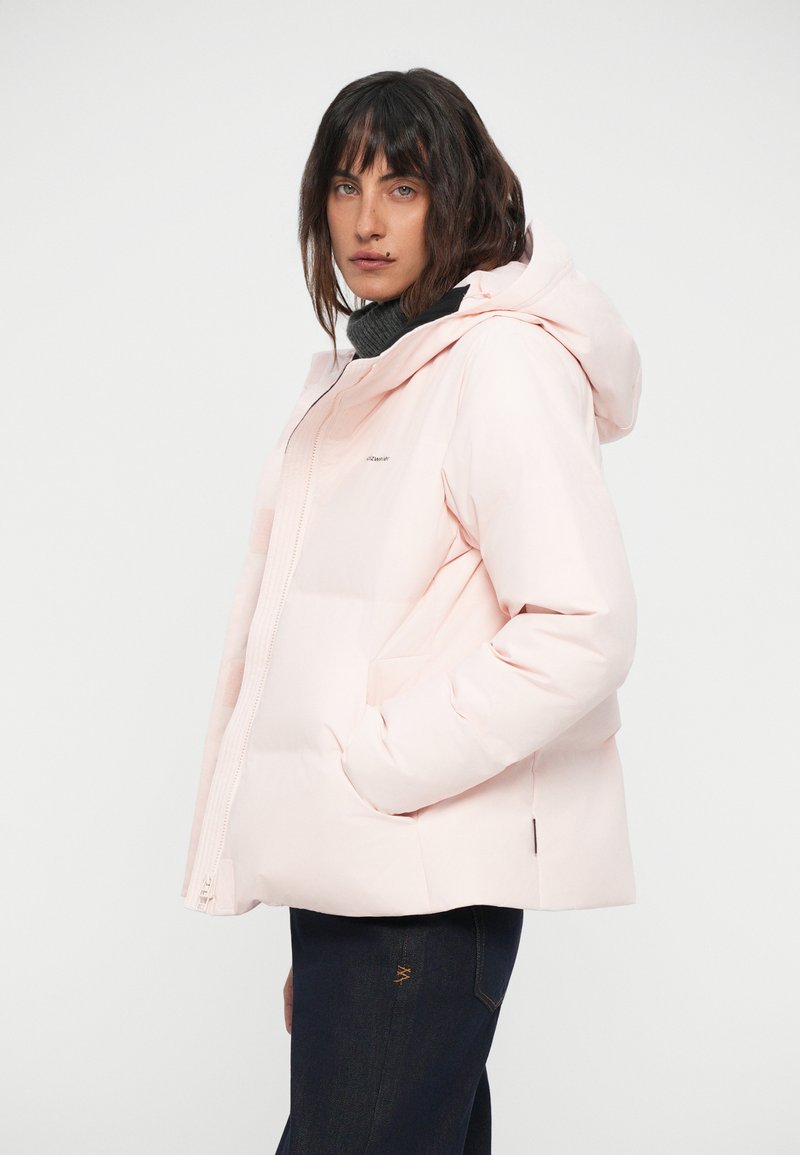 Doudoune rose clair avec capuche, dotée d'une fermeture zippée et de deux poches latérales. Tissu doux avec une finition lisse. Silhouette décontractée.