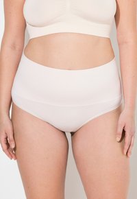 Hochgeschnittene nahtlose Unterwäsche aus weichem beigen Stoff, mit einer glatten Textur und minimalen Nähten, die für Komfort und Abdeckung sorgt.