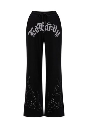 Zwarte trainingsbroek met een trekkoord in de taille en een groot zilverkleurig "Ed Hardy" logo. Versierd met studs in vlampatronen langs de benen.