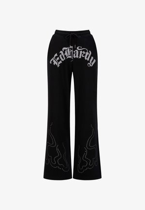 Zwarte trainingsbroek met een trekkoord in de taille en een groot zilverkleurig "Ed Hardy" logo. Versierd met studs in vlampatronen langs de benen.