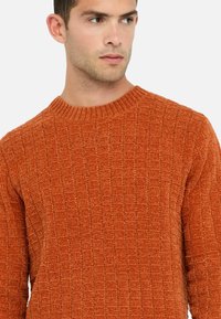 Orangefarbener, strukturierter Pullover mit Karomuster, geripptem Rundhalsausschnitt und langen Ärmeln, aus weichem, gestricktem Stoff.