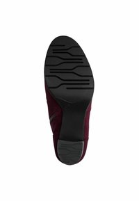 Chaussure en daim bordeaux avec une semelle en caoutchouc noir présentant un motif texturé pour l'adhérence, détail de fermeture éclair sur le côté et design à bout rond.