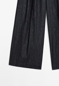 Dark denim wide-leg trousers with a textured surface and pleated front design. Features a high waist and minimal hardware accents.