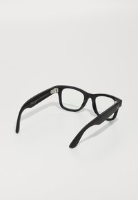 Black rectangular eyeglasses with clear lenses. Thick matte frames and wide temple arms feature a small metal logo detail.