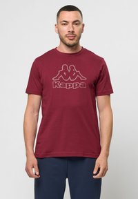 Bordo pamut póló rövid ujjakkal, az elején egy nagy Kappa logo kontrasztos színben. Egyszerű dizájn, kerek nyakkivágás.
