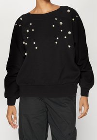 Felpa nera con scollatura ampia e maniche lunghe, decorata con perle e cristalli sulla parte anteriore e sulle spalle.