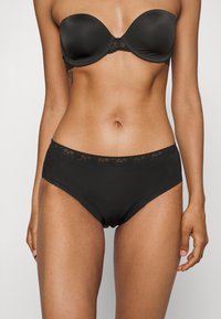 Svart utan axelband BH med spetsdetaljer och höga svarta trosor, slät textur, åtsittande design och minimal dekor.