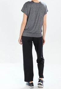 Top gris de manga corta con un corte relajado, combinado con pantalones negros de corte holgado. Zapatillas deportivas negras completan el conjunto.