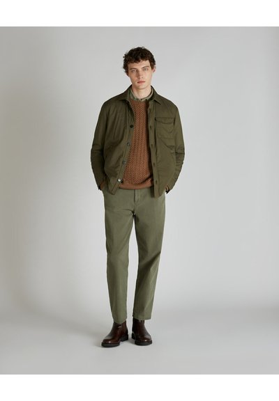 Veste olive, pull en tricot marron, pantalon vert clair et bottes marron ; design simple avec tricot texturé et détails de boutons.