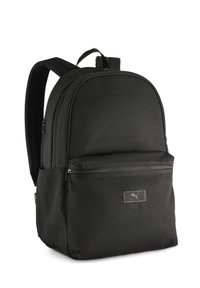 Mochila negra hecha de tela duradera, con forma redondeada, dos compartimentos con cremallera y un discreto parche de logo en la parte frontal.
