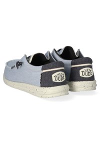 Scarpe slip-on in tela blu chiaro con tacco blu scuro, suola in gomma maculata e una patch con logo sul retro. Design semplice con cuciture in vista.