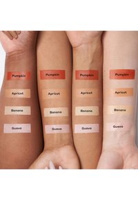 Cuatro brazos muestran muestras de maquillaje en tonos: Calabaza (naranja oscuro), Albaricoque (durazno), Plátano (crema) y Guayaba (rosa claro), etiquetados claramente.
