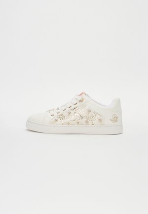 Sneaker bianco con motivo a fiori ritagliato e dettagli dorati. Presenta lacci rotondi, suola testurizzata e un tab posteriore verde chiaro.