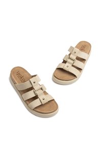 Sandalias tipo slip-on de ante beige con dos correas anchas, herrajes en tono dorado y plantilla acolchada. Plantilla texturizada y suela de color claro.