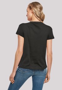 Black short-sleeve t-shirt with a classic round neckline, soft texture, and a relaxed fit, paired with blue slim-fit jeans.