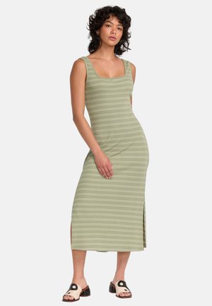 Robe midi côtelée verte avec des rayures horizontales blanches, décolleté carré et fente sur le côté ; associée à des sandales à glissière noires et crème.