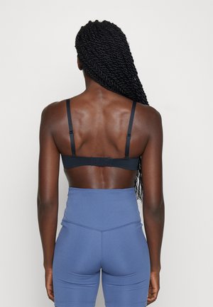 Black bra with adjustable straps and a hook-and-eye closure, paired with high-waisted blue leggings featuring smooth, stretchy fabric.