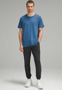 Blå tekstureret kortærmet t-shirt parret med sorte tapered bukser og hvide sneakers. Simpelt design, afslappet pasform, letvægtsmateriale.