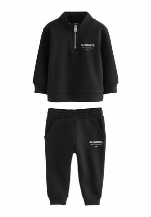 Czarny zestaw z bluzą na zamek i dopasowanymi spodniami. Bluza ma ribbed kołnierz i logo. Spodnie mają elastyczny pas i kieszenie.