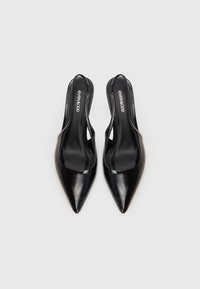 Melnas slēgta pirksta slingback kurpes ar ādas tekstūru un zemu papēdi, skatītas no augšas uz vienkārša fona.