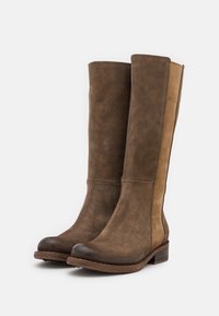 Botas altas marrones hechas de ante con un acabado suave, que cuentan con un panel en tono beige contrastante, puntera redonda y un tacón bajo de madera.