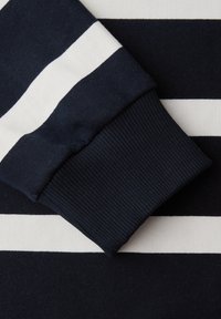 Tissu à rayures horizontales bleu marine et blanc avec un bord-côte bleu marine plié sur les rayures.