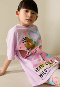 Gaiši rozā oversized t-krekls ar krāsainiem abstraktiem dizainiem un tekstu. Izgatavots no mīksta auduma, ar īsām piedurknēm un vaļēju piegriezumu.