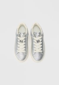 Baskets argentées pailletées avec des lacets et un revêtement crème. Bout rond, semelle plate, avec un accent logo central sur les lacets.