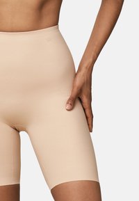 Beige naadloze fietsshorts gemaakt van rekbare, gladde stof, met een hoge taille en een lengte tot halverwege het bovenbeen, voorzien van een zachte textuur.