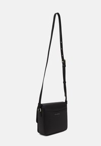 Czarna torebka na ramię wykonana z gładkiego materiału, w kształcie prostokąta, z regulowanym paskiem, złotym wykończeniem i subtelnym logo na przodzie.