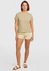 Beige cotton t-shirt with a round neckline and short sleeves, paired with light yellow textured shorts featuring white accents.
