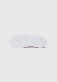 Semelle de sneaker blanche avec un motif en chevrons et le logo "PUMA" embossé près du talon, sur un fond blanc propre.