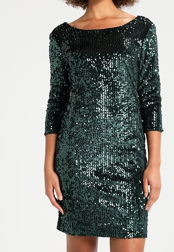 Femme portant une robe vert foncé à sequins, longueur genou, manches trois-quarts et encolure bateau.