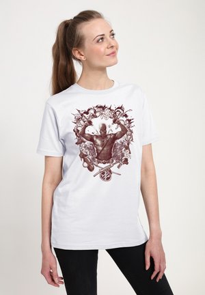 Jeune femme aux longs cheveux portant un t-shirt blanc avec une illustration stylisée de Deadpool tenant deux épées.