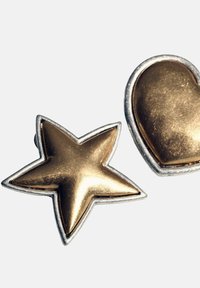 Broches dorées en forme d'étoile et de cœur avec une surface polie et un contour argenté. Le cœur présente un contour arrondi pour une finition lisse.