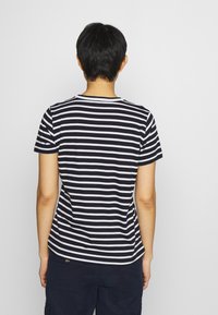 T-shirt a righe in bianco e nero, a maniche corte, con scollatura a girocollo e vestibilità comoda. Tessuto di cotone morbido con strisce orizzontali.