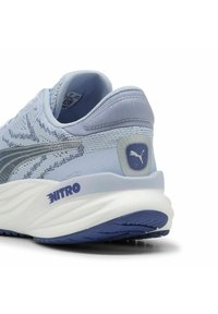 Scarpa sportiva azzurro chiaro con tomaia in tessuto testurizzato, logo Puma ben visibile e branding NITRO sulla suola intermedia bianca imbottita.