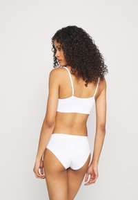 Bralette blanco sin costuras y bragas a juego con tirantes delgados y un ajuste cómodo. Textura suave con un diseño minimalista.